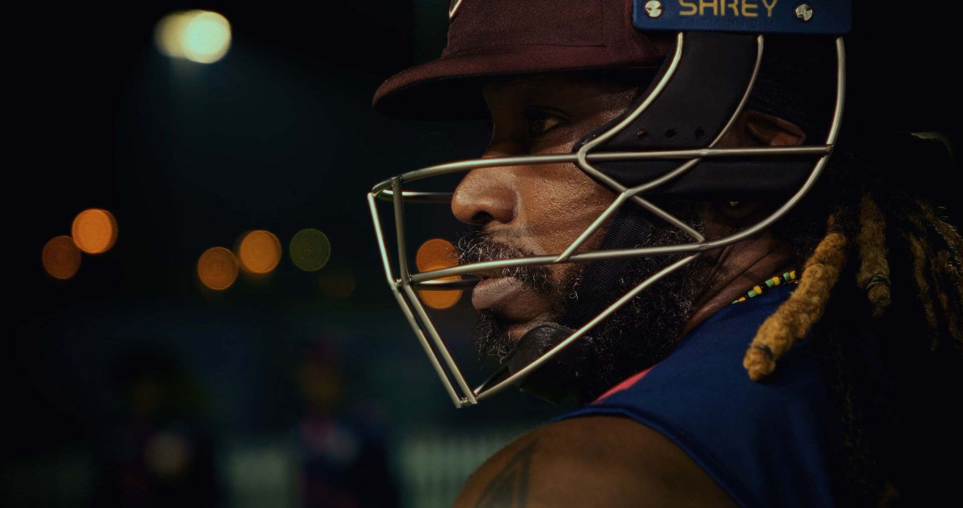 Chris Gayle in profile in his batting helmet, under night-time stadium lights.